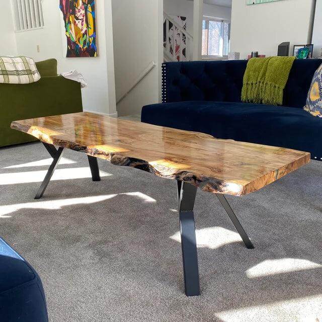 Y-shaped coffee table legs holding a live-edge wooden table top in black