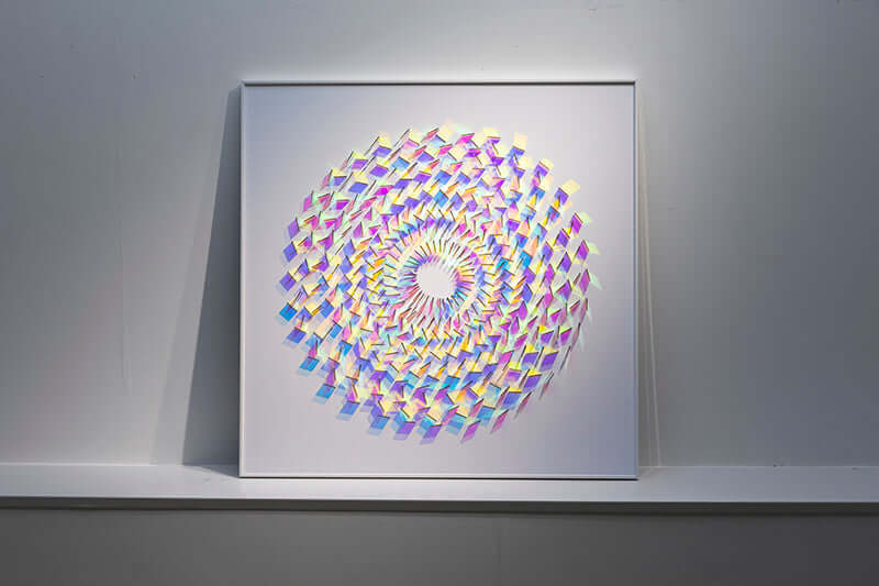 Framed square wall art showing holographic rainbow spiral pattern with white center