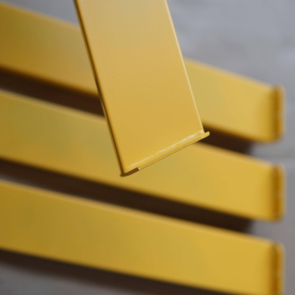 Angled coffee table leg, yellow powder-coated with angled foot and edge seam detail