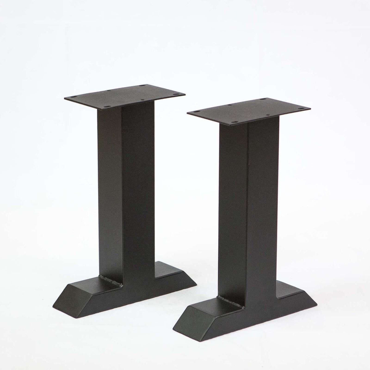 Pair of black T-shaped bench legs with wide mounting plates and angled, flat foot supports